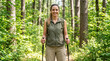 © Len_mik - Smiling young woman hiking in lush green forest. Female trekker with backpack and trekking poles on outdoor trail. Active lifestyle and adventure concept