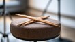 © Burhan - Crossed wooden drumsticks rest on a textured, round seat stool