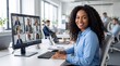 © julijadmi - African American woman smiles while participating in a video conference on a computer in a modern office environment with colleagues visible