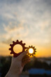 © sommart - Hand holding wooden gears against the sunset sky. Concept of business strategy, cooperation, teamwork, efficient process, and engineering solutions for successful project management and development.