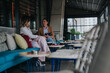 © qunica.com - Two female colleagues meet for a remote work discussion while seated in a modern outdoor cafe. They chat and review notes and a tablet during a relaxed business conversation.