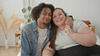 © Krakenimages.com - Plus size woman sits on bed with arm around man, smiling toward camera, holding his hand and showing ring in a bright bedroom building; love together.