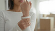 © Krakenimages.com - Young woman holding wrist and gripping sleeve beside stacked cardboard boxes inside building; moving stress.
