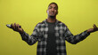 © Krakenimages.com - Young black man holding electric screwdriver with outstretched arms against yellow studio backdrop, eyes closed and expressive; contemplation.
