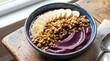 © Dlondong - Acai smoothie bowl topped with sliced bananas and crunchy granola.