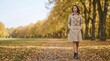 © Xenia - Woman wearing a stylish beige trench coat and brown boots walking in an autumn park. Classic fall fashion trends. Seasonal outdoor lifestyle