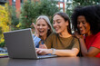© Nenad - Young diverse female students using laptop for AI startup in city