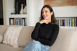 © gzorgz - Smiling brunette haired woman relaxing on a sofa in her modern home interior