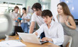 © JackF - Team of employees gathers around single laptop, looking at screen and collaborating on common project or problem