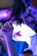 © ultramansk - A diverse, multiethnic software team gather to look at a device together in a modern technology office bathed in blue light, a portrait of inclusion and collaboration in modern tech