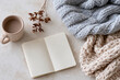 © lashkhidzetim - Cozy knitted blanket rests beside an open notebook. Warm mug of tea sits nearby, steam gently rising. Dried flowers add a soft, natural touch to the scene. Soft lighting enhances the peaceful