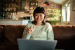 © Davor - Smiling woman on video call in living room at home
