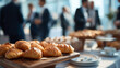 © KotBaton - Fresh buttery croissants displayed during a corporate breakfast buffet with business professionals networking in the background. Hospitality, catering and business event concept.