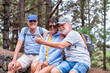 © luciano - Group of three smiling senior adults enjoying outdoor activity and taking a selfie using a smartphone while resting during a hike in the forest