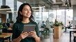 © Eve - Happy young Latina businesswoman holding digital tablet, smiling in modern coworking open space office. Confident female entrepreneur working online, using touchscreen device, looking away.