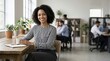 © Xenia - Smiling young Black businesswoman sitting at a desk in a modern office. Professional woman wearing a geometric striped shirt holding a coffee mug. Corporate teamwork and collaboration concept