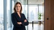 © ASA - Professional businesswoman standing with arms crossed in modern office