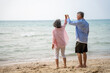 © SKW - Happy Senior Asian Couple Dancing Joyfully on the Beach, Retirement Travel Lifestyle