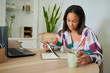 © KikoStock - Woman working from home reviewing notes and drinking coffee