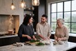 © AdPremium - Happy multi-generational family cooking together in a stylish modern kitchen, preparing a meal with fresh ingredients and homemade dough