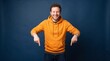 © Creative Stocker - A cheerful young man with curly hair wearing a bright orange hoodie, pointing his index ad social media download thambnail template event festive festival 2026 2027 2028
