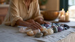 © forenna - crystal therapy practitioner arranging polished stones on a treatment table in a candlelit wellness studio, soft shadow across linen surfaces, single professional at work,