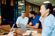 © we.bond.creations - Multicultural professional colleagues discussing work, sharing ideas, and brainstorming during a business meeting in a contemporary workspace