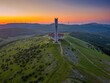 © robertharding - Drone view of Buzludzha monument atop a mountain during sunset with wind turbines in the distance in Bulgaria