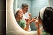 © Marko Geber - Couple brushing teeth together at home bathroom mirror