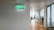 © Hossen - Bright green illuminated exit sign mounted on white wall of a contemporary professional office corridor with emergency, corridor