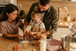 © La Famiglia - Family baking together in kitchen, child cracking egg