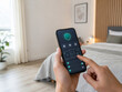 © milanchikov - Control de hogar inteligente en una habitación moderna con un smartphone en la mano