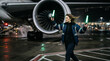 © Maxime - Femme marshall guidant un avion de ligne la nuit sur le tarmac d'un aéroport