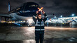© Maxime - Femme agent de piste avec bâtons lumineux guidant un avion de ligne la nuit