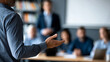 © Laura - Faceless business trainer facilitating a leadership development workshop for a group of managers in a corporate training room, defocused training environment in background,