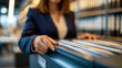 © Laura - Faceless professional woman in a corporate blazer organizing files in a filing cabinet, administrative efficiency concept, defocused professional office in background, corporate