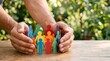 © mcjanuald - Family life insurance and community protection concept with hands sheltering paper family figures