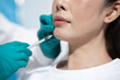 © NanSan - Close up of a woman getting a facial injection from a medical worker wearing gloves in a clean clinic setting