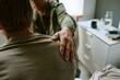 © AnnaStills - Young adult man receiving supportive shoulder touch during consultation in military hospital, representing recovery and care. Useful for veteran healthcare, trauma support, rehabilitation campaigns