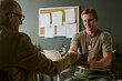 © AnnaStills - Young adult Caucasian soldier signing document during consultation in military hospital, representing patient care and recovery. Ideal for veteran healthcare, insurance, support services