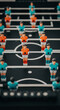 © PhotoArtHub - Foosball figures in teal and orange, arranged on a black field with white lines, symbolizing competition and indoor recreation
