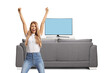 © Ljupco Smokovski - Excited woman standing in front of a tv screen and gesturing happiness with raised arms
