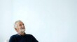 © Yuliia - Senior man with gray hair and beard, wearing dark navy sweater, looking upward thoughtfully against white background. Suitable for healthcare, wellness, aging, retirement, and lifestyle editorial use.