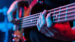 © bastet - Close-up of hands playing bass guitar in colorful stage lighting