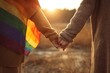 © Rawpixel.com - Two people holding hands with a rainbow flag in a sunny field.