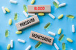 © Natallia - Blood Pressure Monitoring symbol. Concept words Blood Pressure Monitoring on wooden blocks. Beautiful blue background with pills. Healthcare and Blood Pressure Monitoring concept. Copy space.