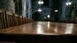 © Isyana - Polished wooden table and rows of chairs in dimly lit, ornate stone hall