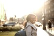 © Cavan Images - Woman looking back and smiling on a sunny city street