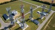 © Wong - An aerial view of multiple telecommunication towers transmitting signals across a green landscape with surrounding buildings and pathways.