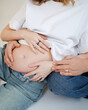 © Aigul Sabirova - A pregnant woman and her partner sit together, touching her bare belly. Commercial concept of prenatal support, partnership, family planning, and love.